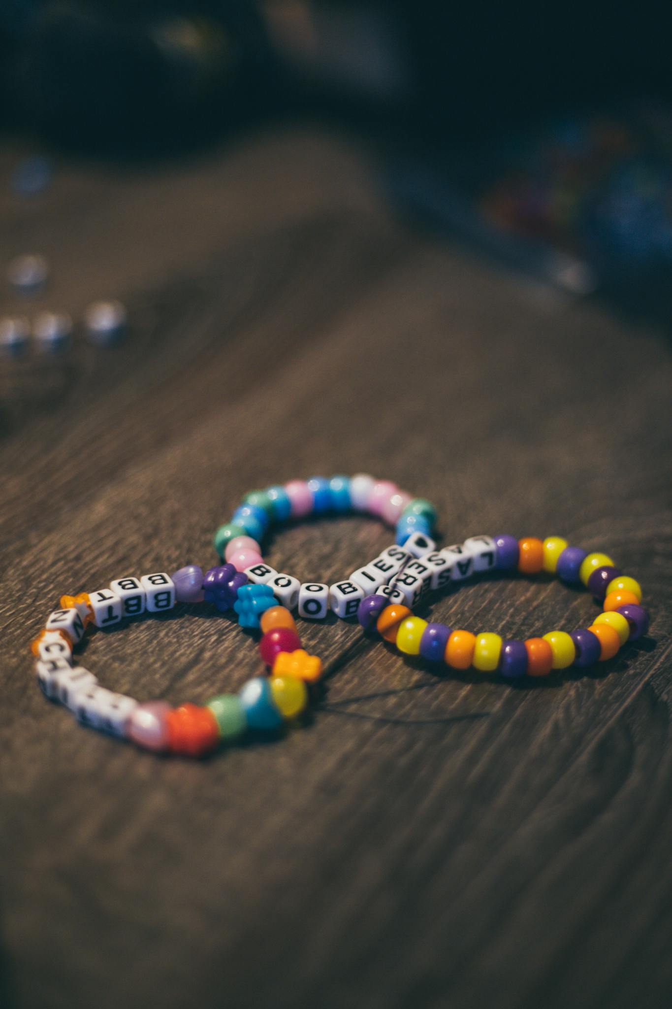 Vibrant bead bracelets featuring letters arranged on a rustic wooden background.